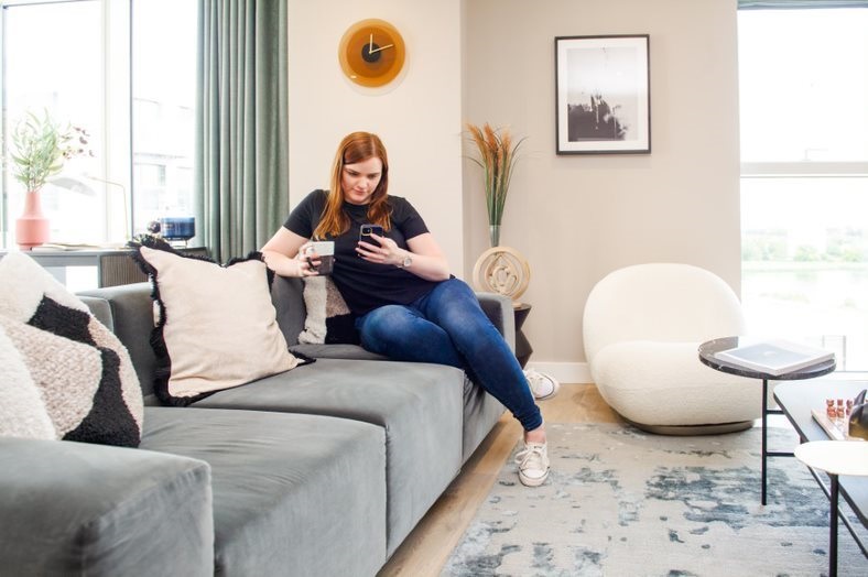 Picture of woman sitting on a sofa looking at her phone