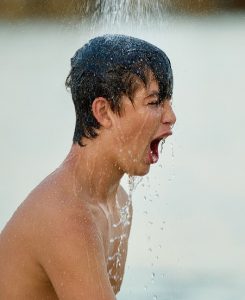 Topless boy having a cold shower