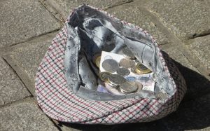 a hat on the ground with coins and banknotes